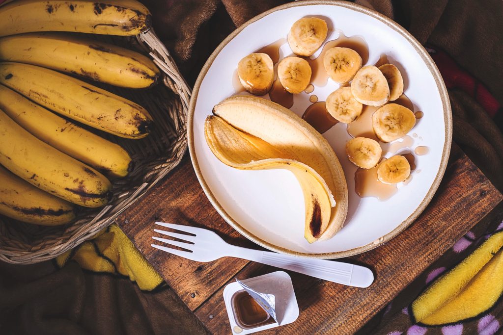 White dish with a peeled banana drizzled with a sauce