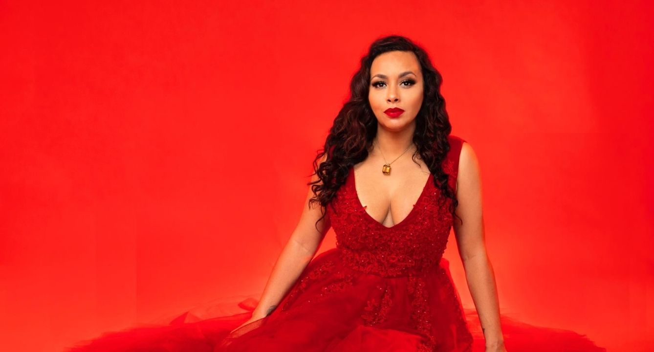 Latina designer sitting with a fluffy red dress